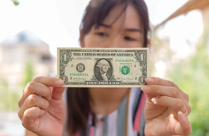 woman holding one dollar bill worth money