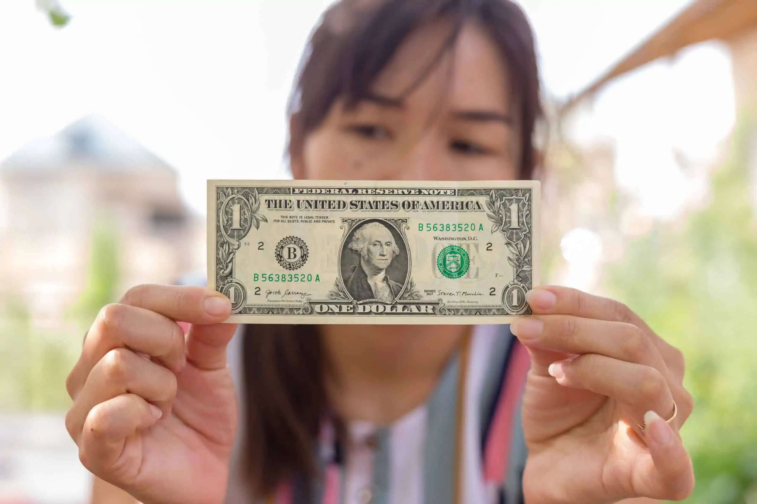 woman holding one dollar bill worth money