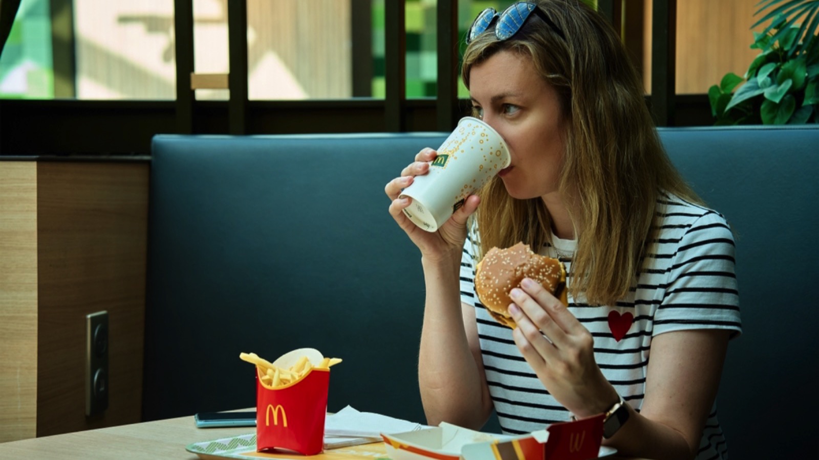 Double-Digit Inflation: 15 Fast Food Items With Super-Sized Price Increases 5 Woman eating in McDonalds