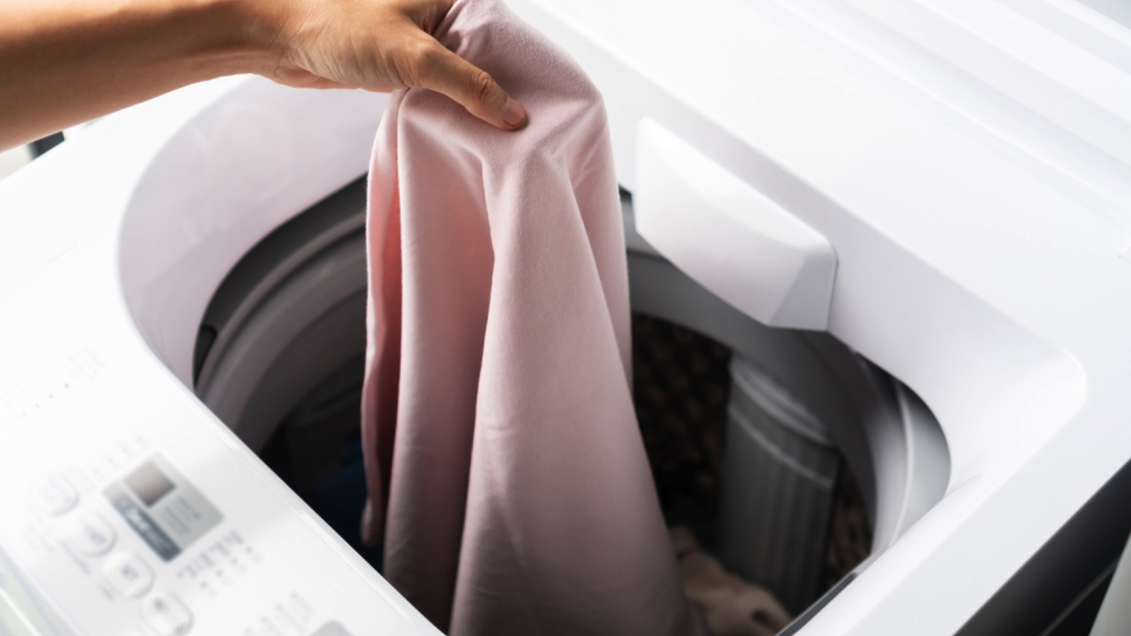 15 Suspiciously Easy Ways to Lower Your Electric Bill 5 Young woman puting clothes in machine