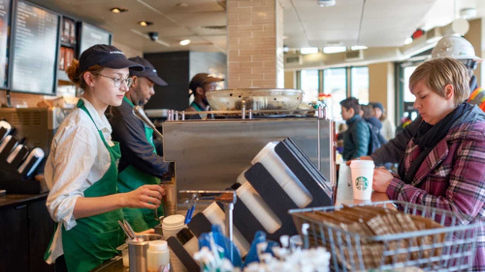 Double-Digit Inflation: 15 Fast Food Items With Super-Sized Price Increases 8 woman buying coffee in Starbucks